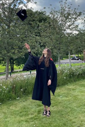 Foto de Georgina con su toga de graduación y lanzando su sombrero al aire 